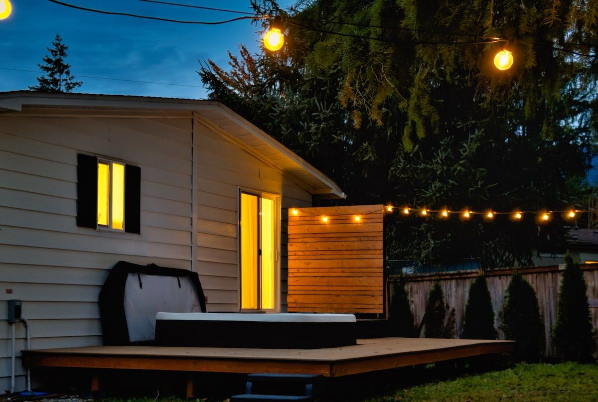 Back of the house with hot tub deck and string lights